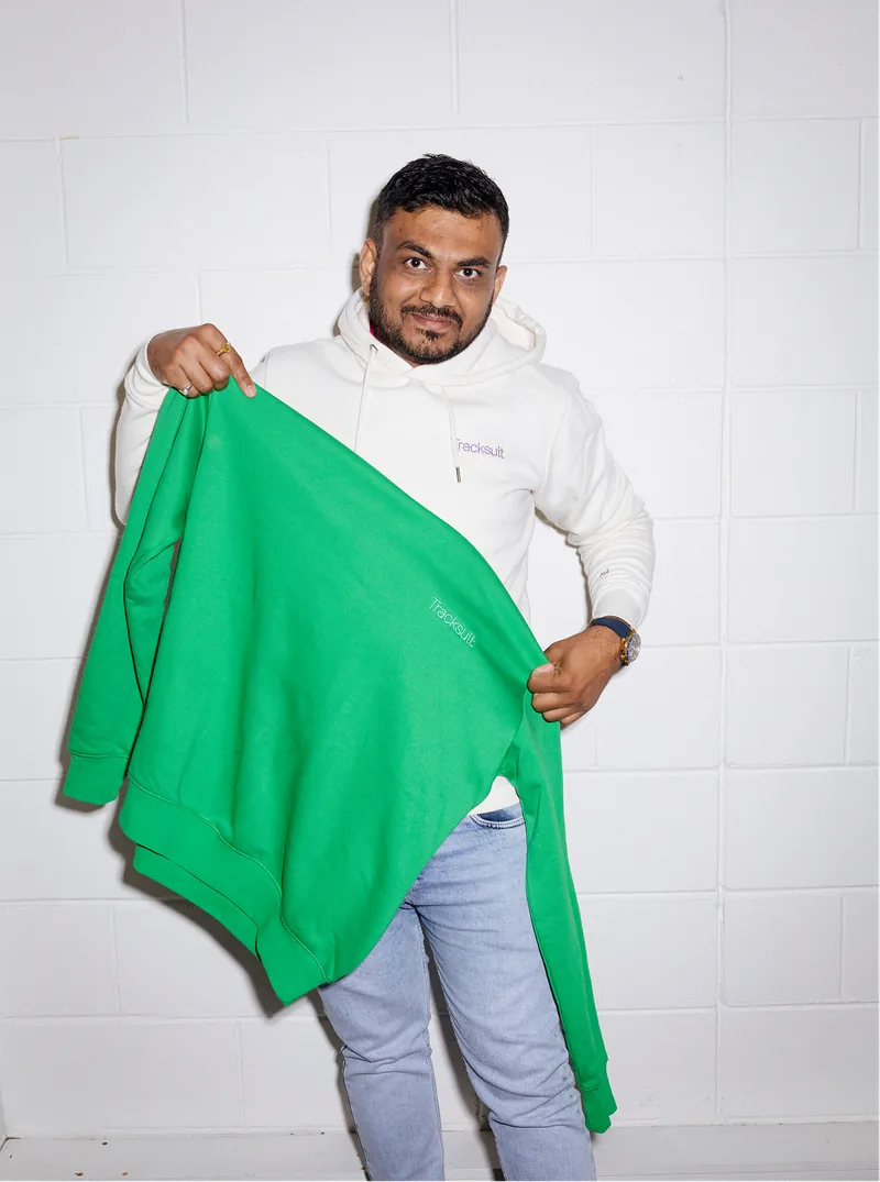 Tracksuit team member holding a green sweatshirt