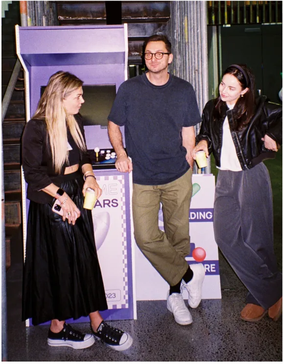 Three people gathered around an arcade machine